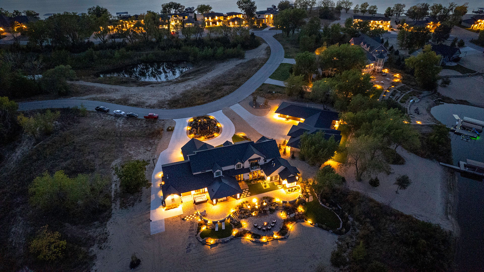 dusk aerial shot of a home on a lake with landscaping designed by omaha's indigenous landscaping